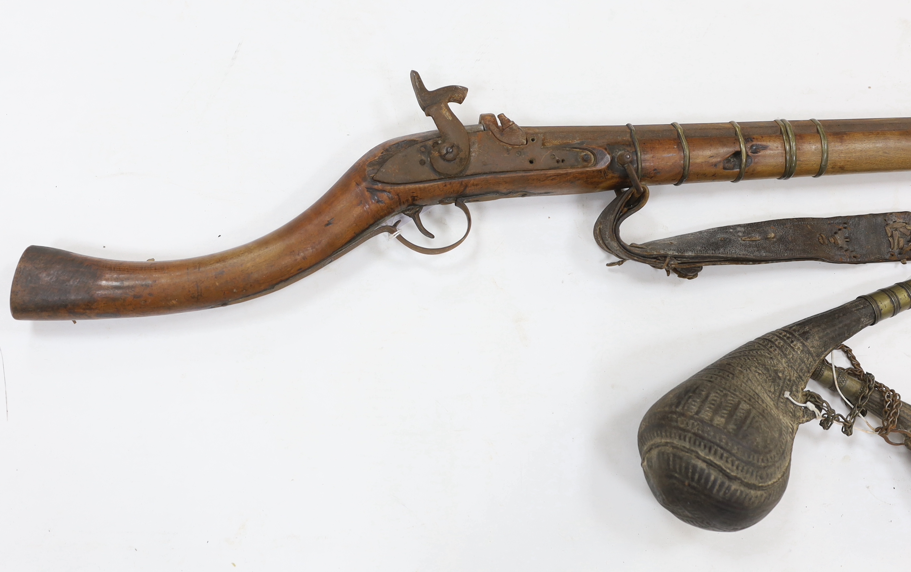An Afghan percussion rifle with octagonal barrel and brass mounts, barrel 105.5cm, together with two leather powder flasks